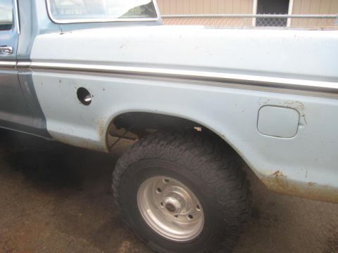 1976 Ford F-250 - Side view of a 1976 Ford F-250 pickup truck, focusing on the rear wheel and bed panel.