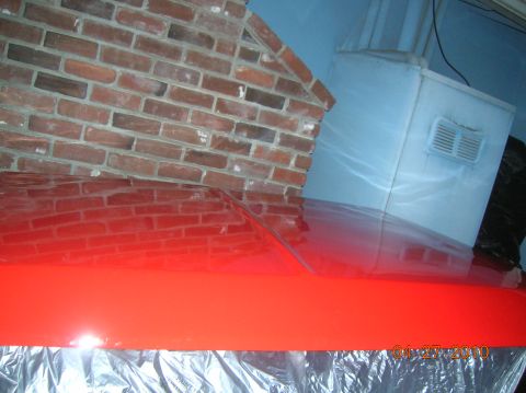 1985 Ford Bronco - A red car hood is shown with reflections of a brick wall and a white appliance.