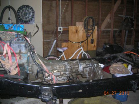 1985 Ford Bronco - Close-up of a vehicle's transmission and frame, with a bicycle visible behind it.