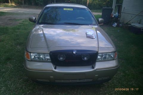 2000 Mercury Grand Marquis - A gold Mercury Grand Marquis is parked outside with papers on its hood.