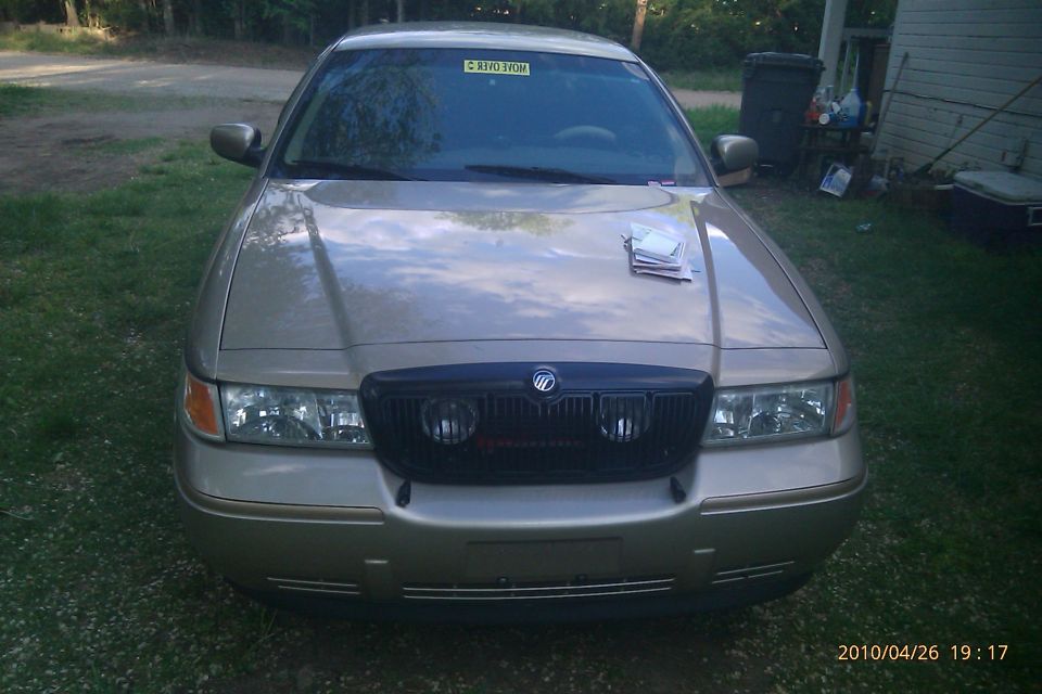 Front view of a gold Mercury Grand Marquis with a black grille. Papers are on the hood