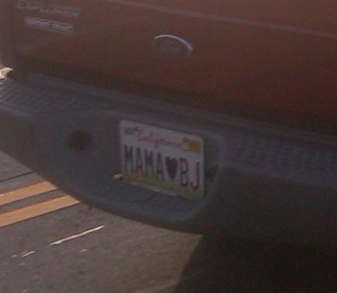 1986 Ford Bronco - A red Ford Explorer's rear bumper displays a personalized California license plate.