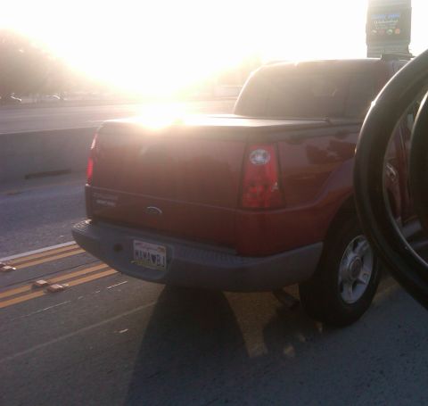 1986 Ford Bronco - Rear view of a red pickup truck with a soft tonneau cover and a personalized California license plate.