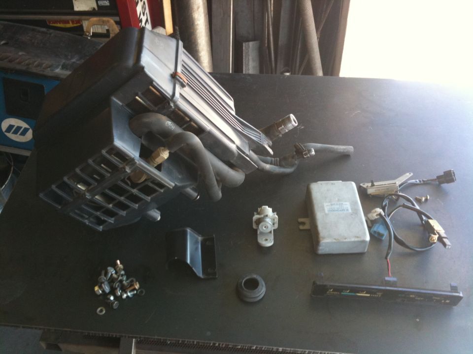 Assorted car parts including an air intake assembly, ECU, and wiring harness laid out on a table