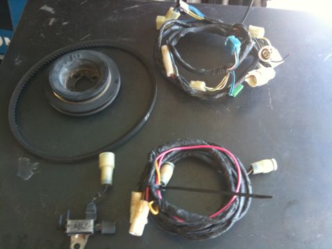 1987 Suzuki Samurai - Several automotive parts, including a belt, pulley, and two wiring harnesses, are displayed on a dark surface.