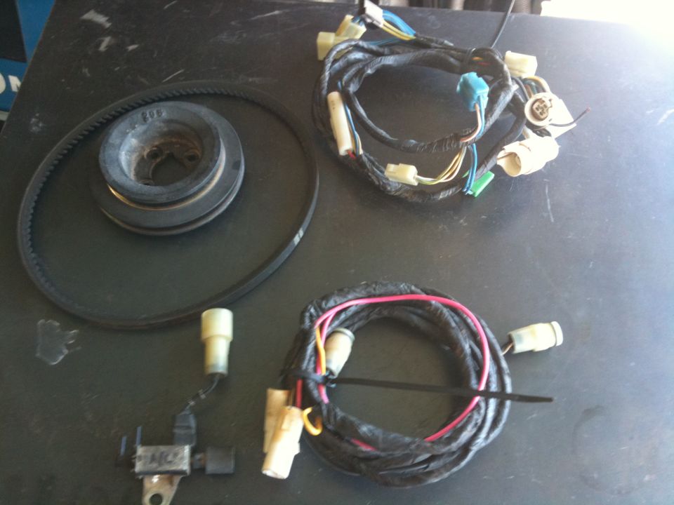 Pulley, belt, and wiring harnesses laid out on a dark surface
