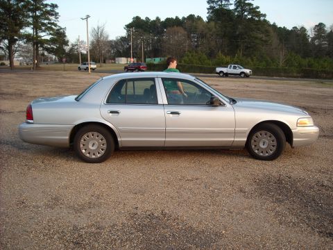 2003 Ford Crown Victoria - Side view of a silver 2003 Ford Crown Victoria parked on a gravel surface.