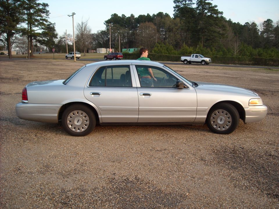 2003 Ford Crown Victoria side profile, silver paint, gravel lot