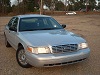 2003 Ford Crown Victoria - A silver 2003 Ford Crown Victoria sedan is parked outdoors on a gravel lot.