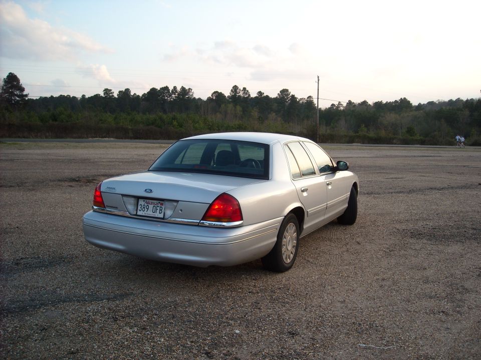 Silver 2003 Ford Crown Victoria parked on a gravel lot, rear view