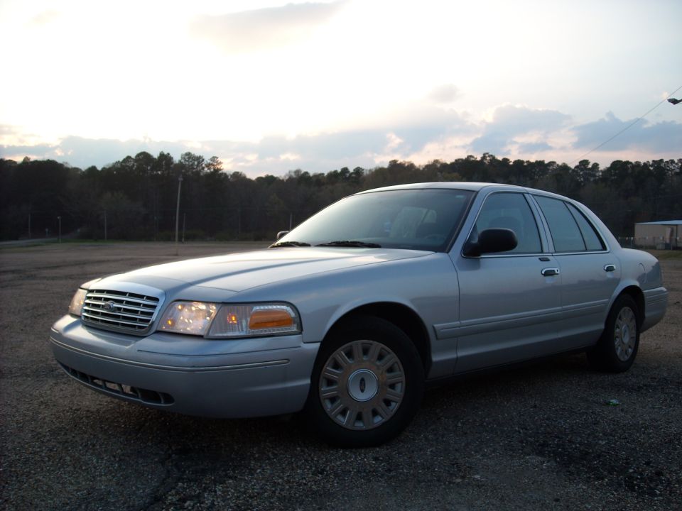Silver 2003 Ford Crown Victoria parked on gravel lot
