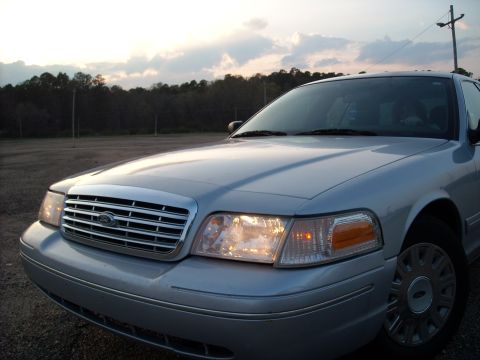 2003 Ford Crown Victoria - The front end of a silver 2003 Ford Crown Victoria is visible under a dusky sky.