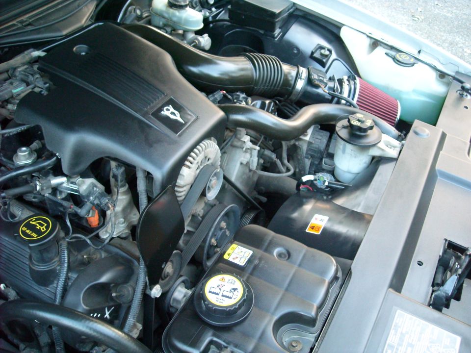 Engine bay of a 2003 Ford Crown Victoria showing the V8 engine, air intake, and coolant reservoir