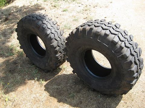 1986 Ford Bronco - Two off-road tires are shown on the ground, likely for sale or replacement.