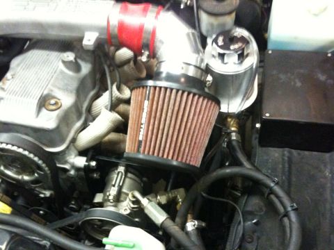 1987 Suzuki Samurai - Close-up of an engine bay an aftermarket air intake system with a red hose and a prominent air filter.