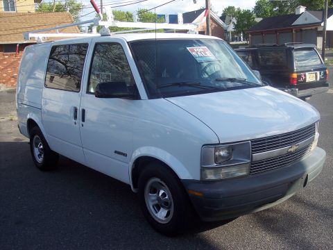 2006 Chevrolet Corvette - A white cargo van is parked on the street with a ladder rack installed. A 'For Sale' sign is visible on the windshield.