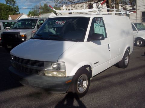 2006 Chevrolet Corvette - A white cargo van is parked on an asphalt lot with other vehicles visible in the background.