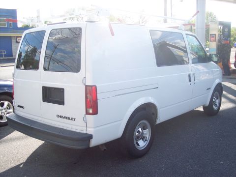 2006 Chevrolet Corvette - White Chevrolet Astro van parked at a gas station, rear view showing roof rack.