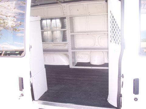 2006 Chevrolet Corvette - View inside a cargo van, equipped with storage shelves and a rubber floor mat.