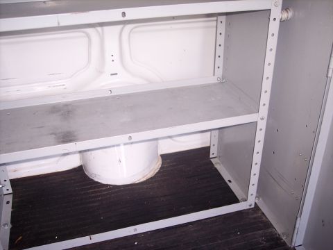2006 Chevrolet Corvette - The interior of a vehicle shows a metal shelving unit with two shelves and a dark floor.