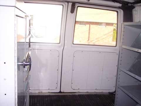 2006 Chevrolet Corvette - Interior view of a white van with shelving and two doors visible.