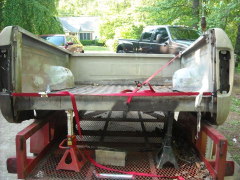 1979 Ford F-150 - A truck bed is strapped down on a trailer, with other vehicles visible in the background.