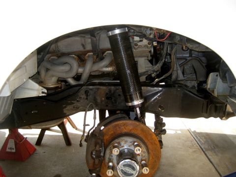 1996 Ford Bronco - The front suspension of a vehicle is shown with the wheel removed, revealing the brake system and engine components.