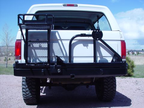1993 Ford Bronco - Rear view of a 1993 Ford Bronco showing aftermarket bumper, spare tire carrier, and cargo rack.