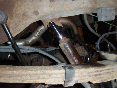 1995 Ford Bronco - Close-up view of the undercarriage, showing worn suspension parts and exhaust system.