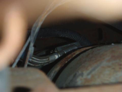1995 Ford Bronco - Detail of automotive wiring and a braided hose, possibly a fuel line or sensor connection.