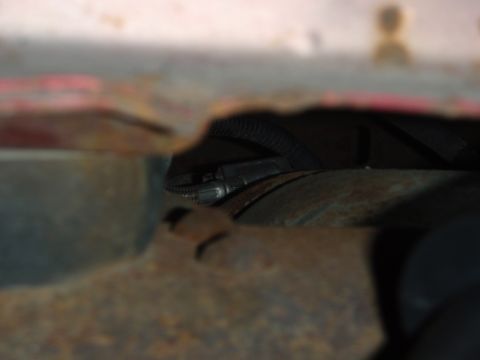 1995 Ford Bronco - The underside of a vehicle shows rust and a black wire loom.