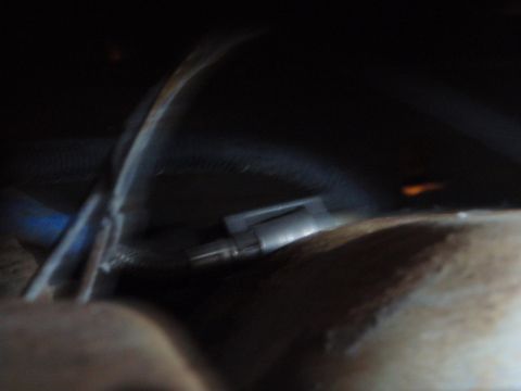 1995 Ford Bronco - A close-up view of a component within the rear suspension system, showing wiring and metal parts.