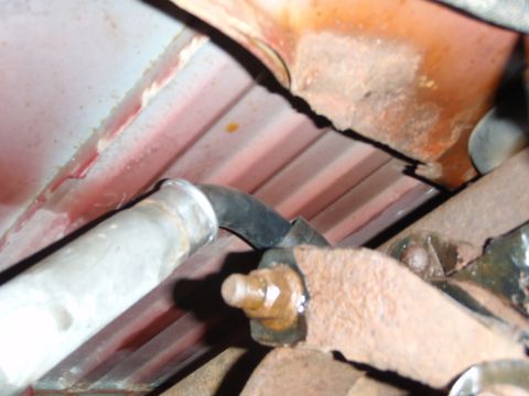 1995 Ford Bronco - Close-up view of the undercarriage, revealing rusted components and a section of piping.