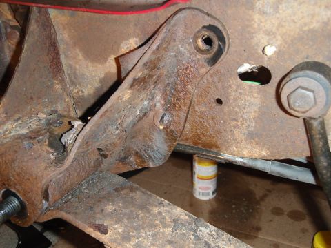 1995 Ford Bronco - Close-up view of a heavily rusted vehicle suspension part, with a can of lubricant visible below.