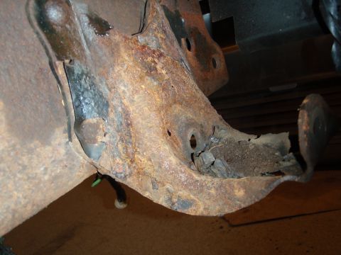 1995 Ford Bronco - This heavily rusted suspension bracket shows significant corrosion and damage, with a green wire visible.