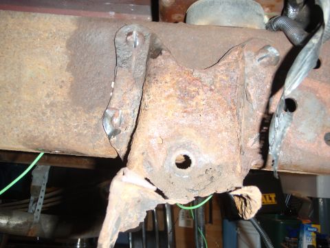 1995 Ford Bronco - Close-up view of a heavily rusted metal bracket and frame component on a vehicle.