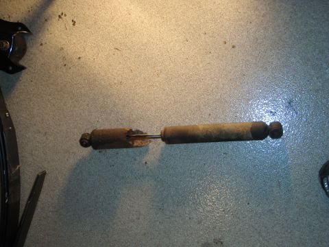 1995 Ford Bronco - A single, worn shock absorber is pictured on a workshop floor.