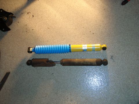 1995 Ford Bronco - A comparison of a new shock absorber with a worn-out one, likely for a vehicle's rear suspension.