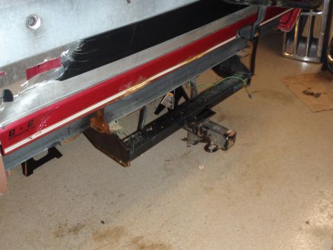 1995 Ford Bronco - The rear of a vehicle shows a trailer hitch and suspension parts, with a red and black trim detail on the bumper.