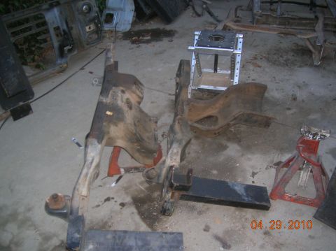1985 Ford Bronco - Disassembled vehicle frame components are supported by jack stands in a workshop setting.