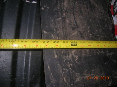1985 Ford Bronco - A measuring tape is used to measure a dark, textured surface, with a date stamp visible in the corner.