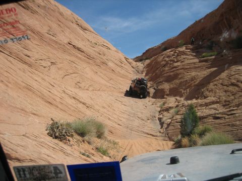 1986 Ford Bronco II - An off-road vehicle navigates a challenging rocky terrain under a bright blue sky.