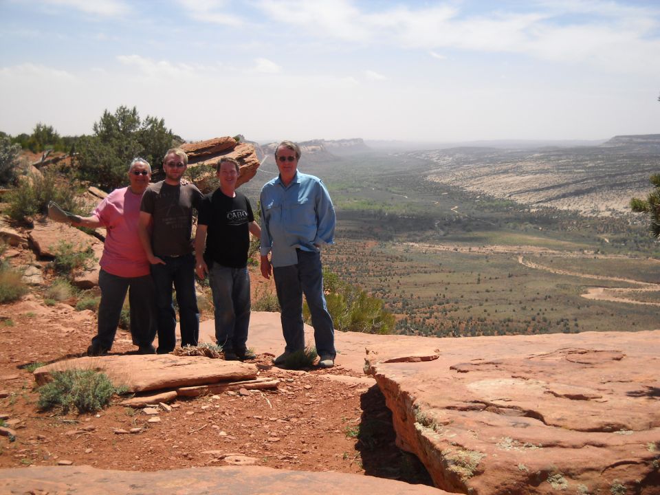 Four men on a rocky overlook with a desert valley below