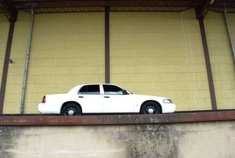 1998 Ford Crown Victoria - Side view of a white 1998 Ford Crown Victoria parked on a raised concrete ledge.