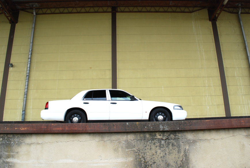 1998 Ford Crown Victoria parked on a ledge against a yellow wall