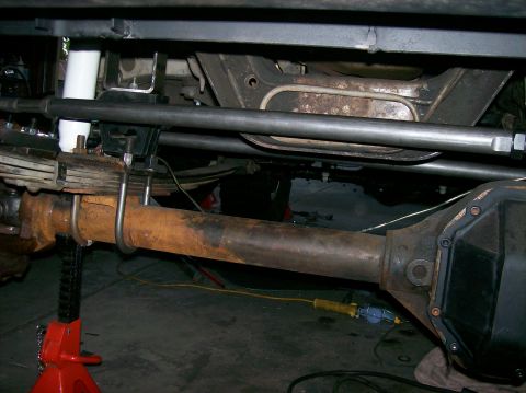 1989 Ford Bronco - The underside of a vehicle shows rusty suspension components and a differential.