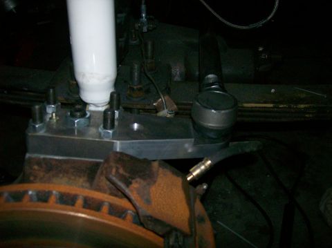 1989 Ford Bronco - Detail view of suspension and brake parts, including a shock absorber and brake rotor.