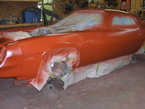 1980 Chevrolet Camaro - A car is being worked on in a garage, with protective coverings over parts of the body and wheels.