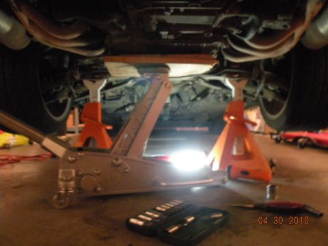 2000 Porsche Carrera - The underside of a vehicle is supported by jack stands and a floor jack, with tools laid out nearby.