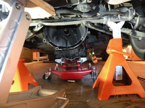 2000 Porsche Carrera - The vehicle's transmission is removed and supported by a red transmission jack, with jack stands holding the car.